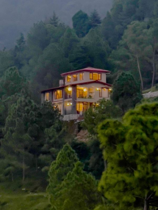 Guldaar Basera at dusk, lights on against the hillside
