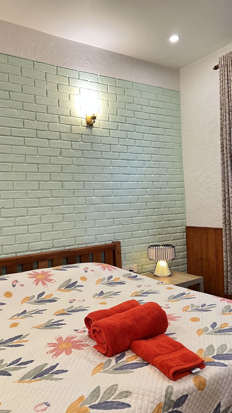 The Buransh room, with a sage green brick wall and floral bedding