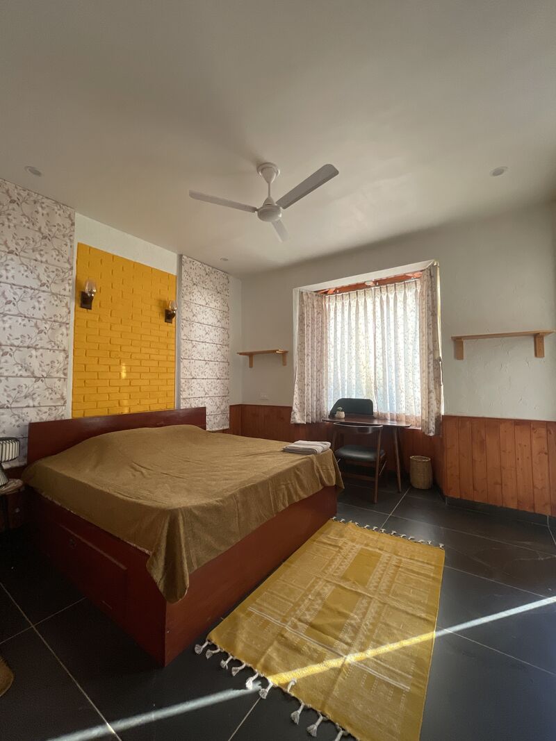 The Fyonli room, with a yellow brick accent wall and a study desk at the window